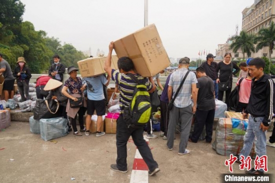 邊民背著物品穿越國界線。王以照 攝